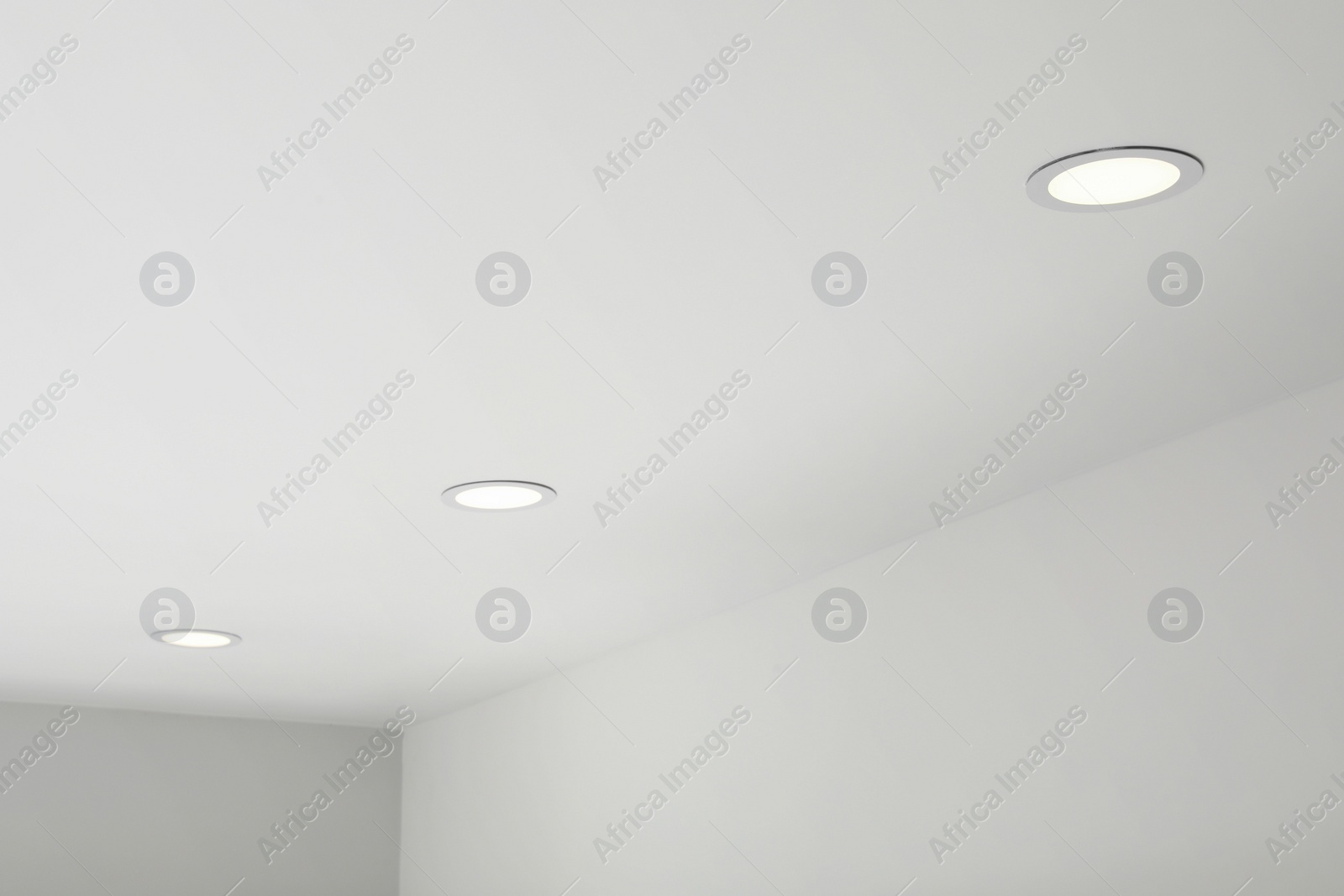 Photo of White ceiling with modern lighting in room, low angle view