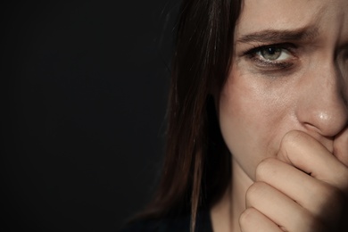 Photo of Crying young woman on dark background, space for text. Stop violence