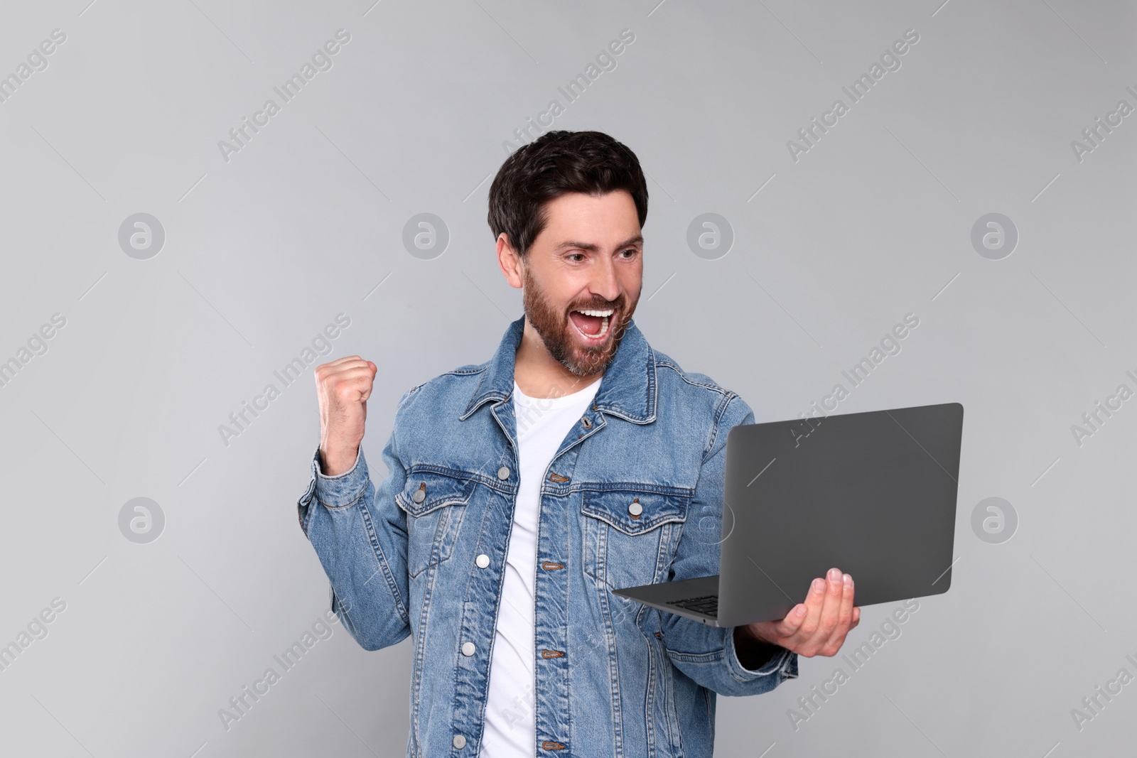 Photo of Emotional man with laptop on light grey background