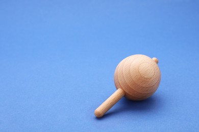Photo of One wooden spinning top on blue background, closeup with space for text. Toy whirligig