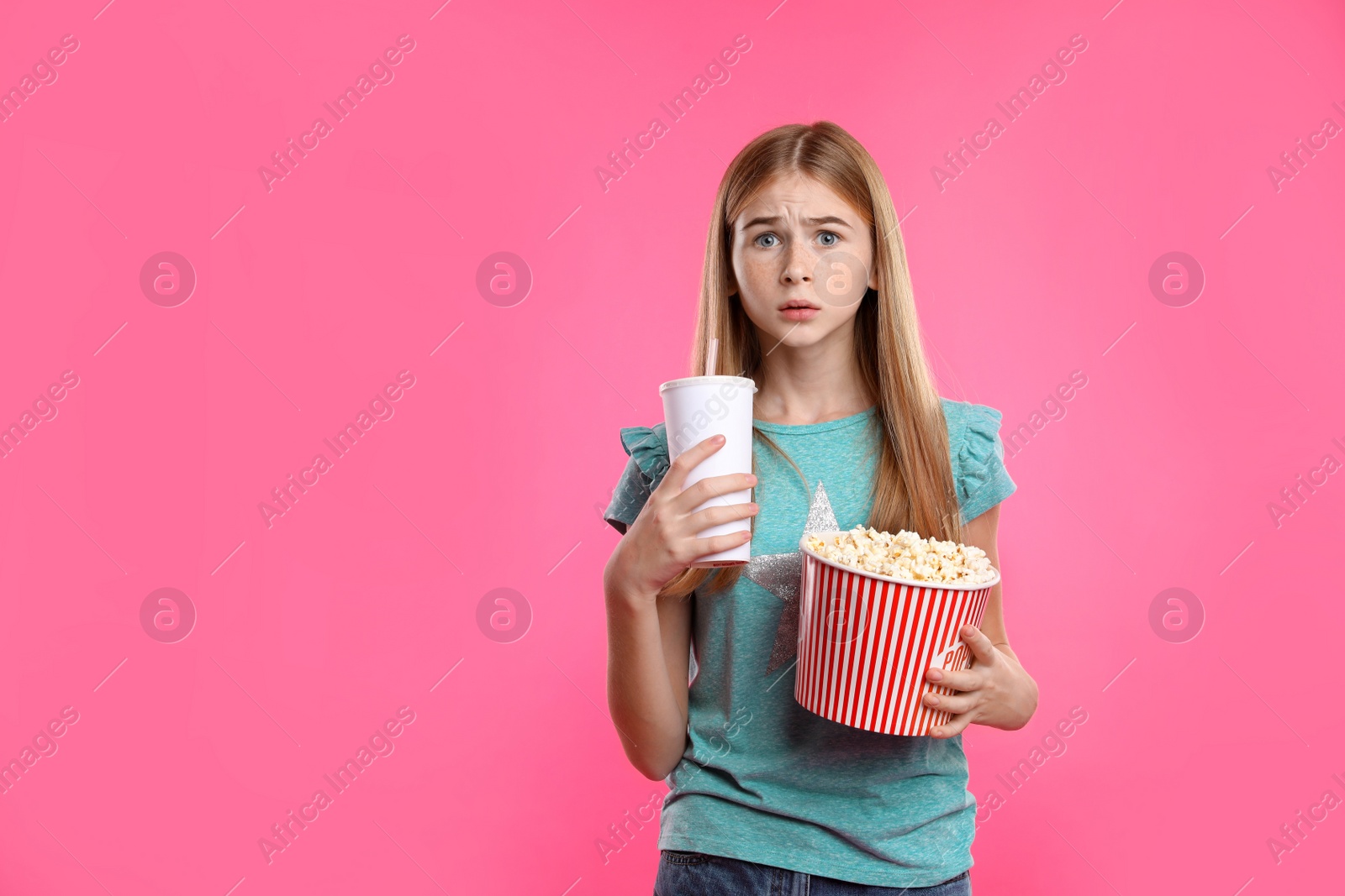 Photo of Emotional teenage girl with popcorn and beverage during cinema show on color background