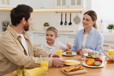 Photo of Happy family having breakfast at table in kitchen