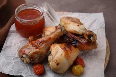Photo of Marinade, roasted chicken drumsticks and tomatoes on brown table