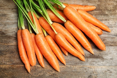 Photo of Ripe carrots on wooden background, top view