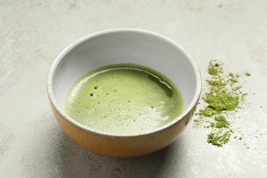 Photo of Cup of fresh matcha tea and green powder on light grey table