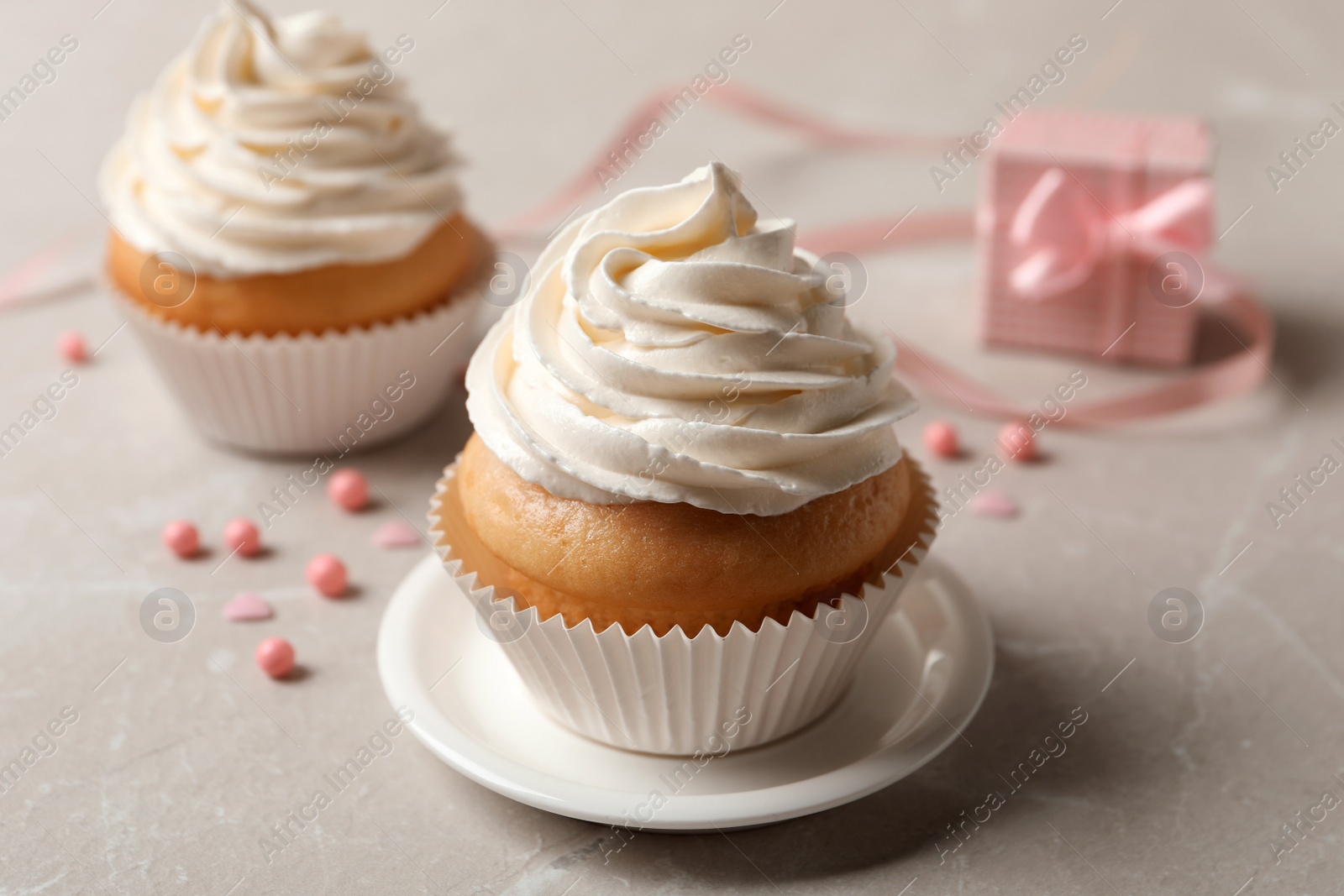 Photo of Delicious cupcakes decorated with cream on light grey table