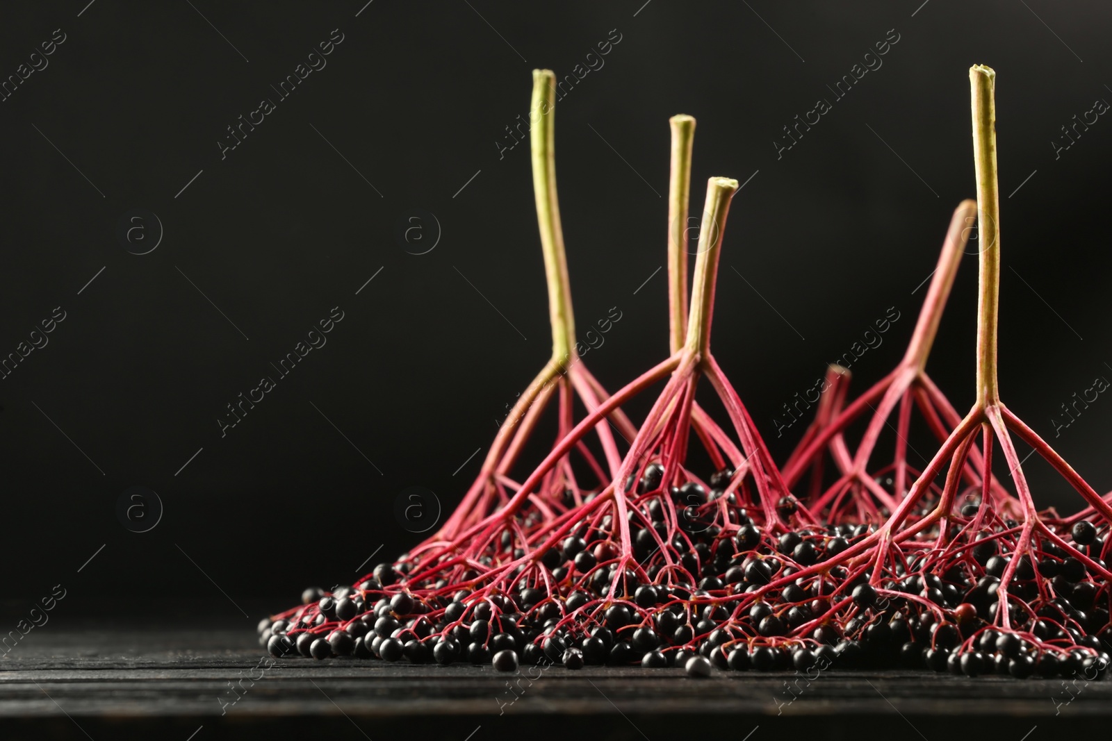 Photo of Bunches of ripe elderberries on black wooden table