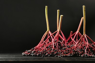 Photo of Bunches of ripe elderberries on black wooden table