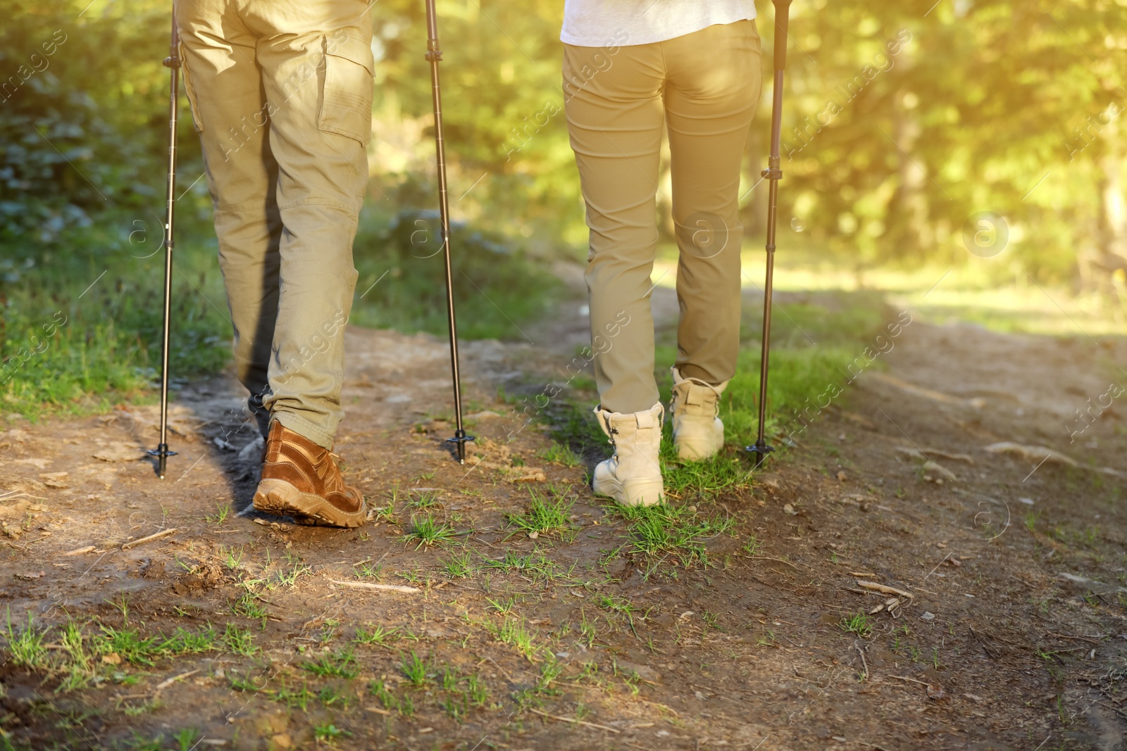 Photo of Couple with trekking poles hiking in forest, closeup