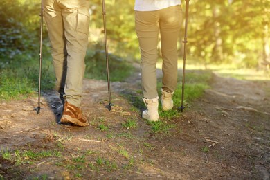 Couple with trekking poles hiking in forest, closeup