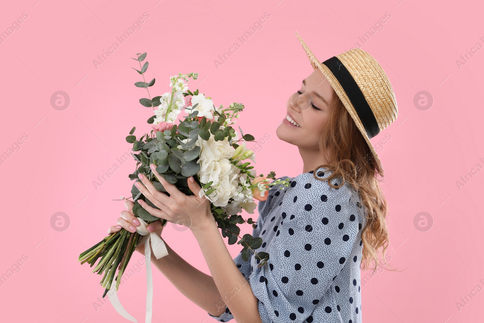Photo of Beautiful woman in straw hat with bouquet of flowers on pink background