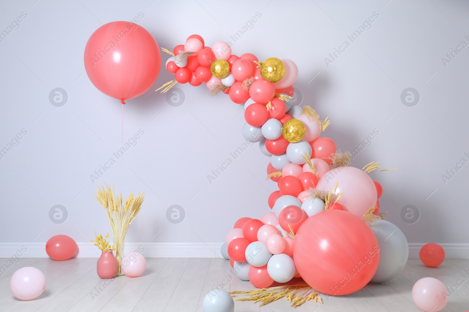 Image of Balloon garland near white wall in room. Festive decor