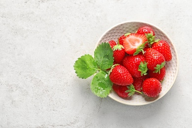 Photo of Bowl with ripe strawberries on light background, top view