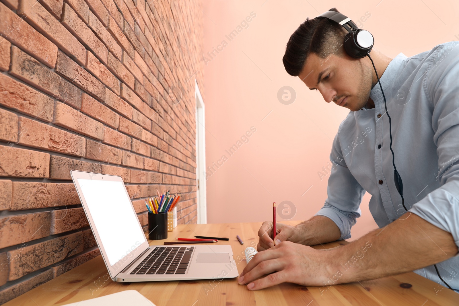 Photo of Man drawing in notebook at online lesson indoors. Distance learning