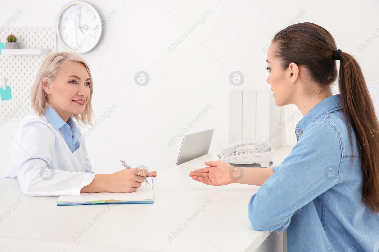 Photo of Senior female receptionist working with client in hospital