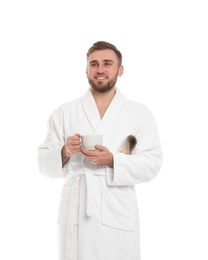 Handsome man in bathrobe with cup of coffee on white background