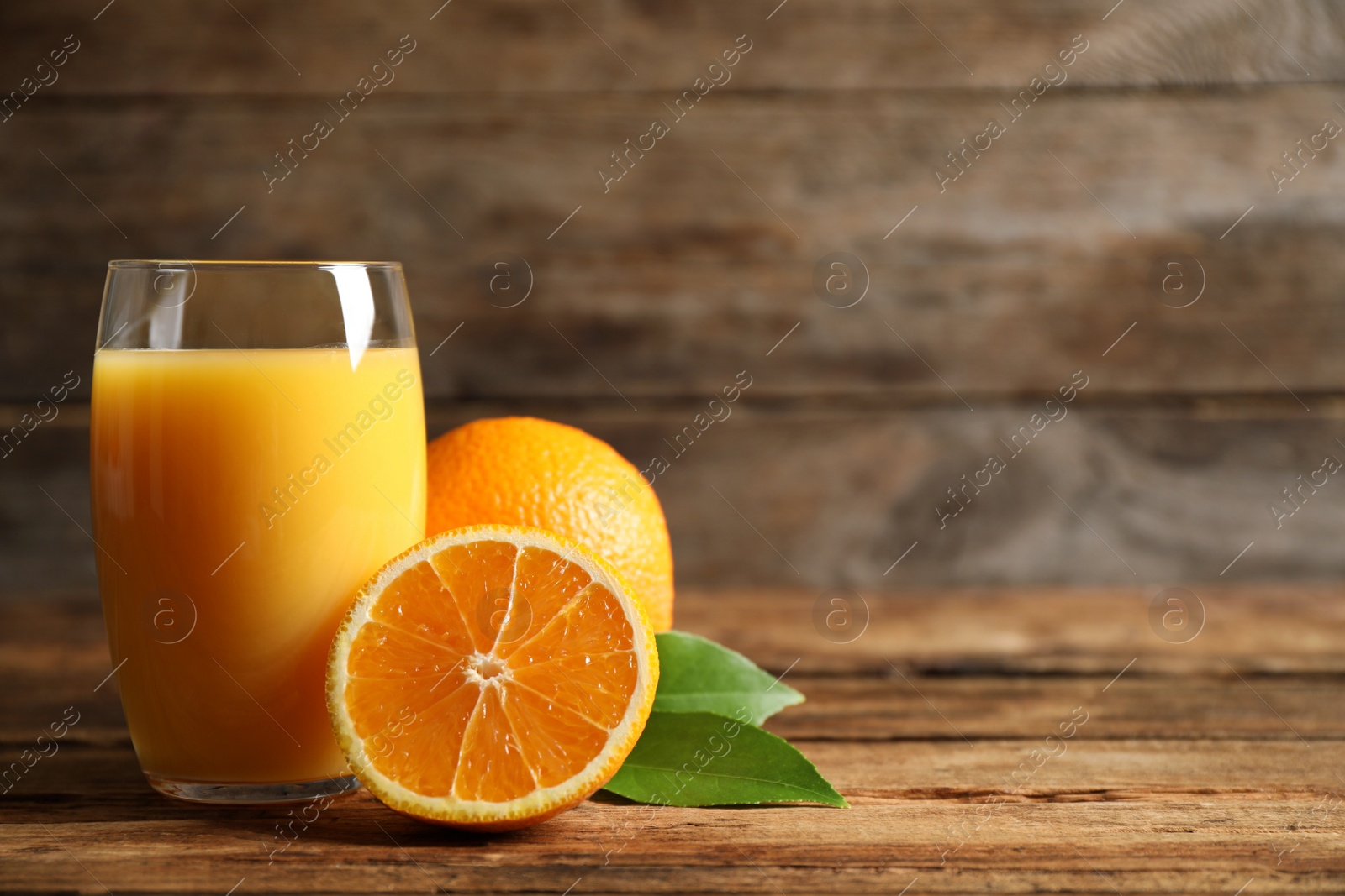 Photo of Glass of orange juice and fresh fruits on wooden table. Space for text