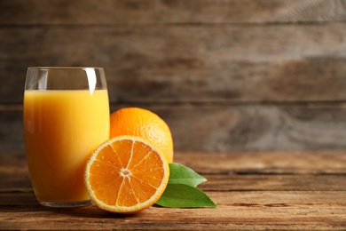 Photo of Glass of orange juice and fresh fruits on wooden table. Space for text