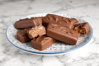 Photo of Delicious chocolate candy bars on white marble table, closeup