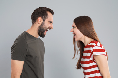 Photo of Couple quarreling on grey background. Relationship problems