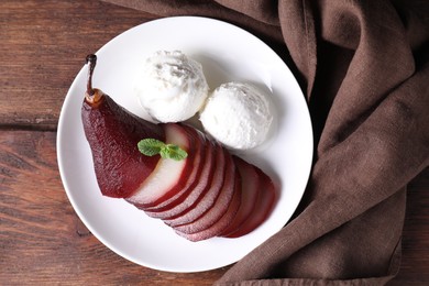 Tasty red wine poached pear and ice cream on wooden table, top view