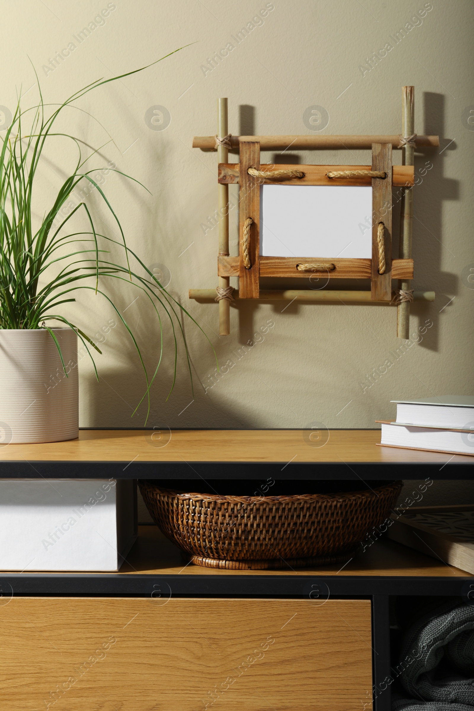 Photo of Stylish room interior with bamboo frame and wooden cabinet