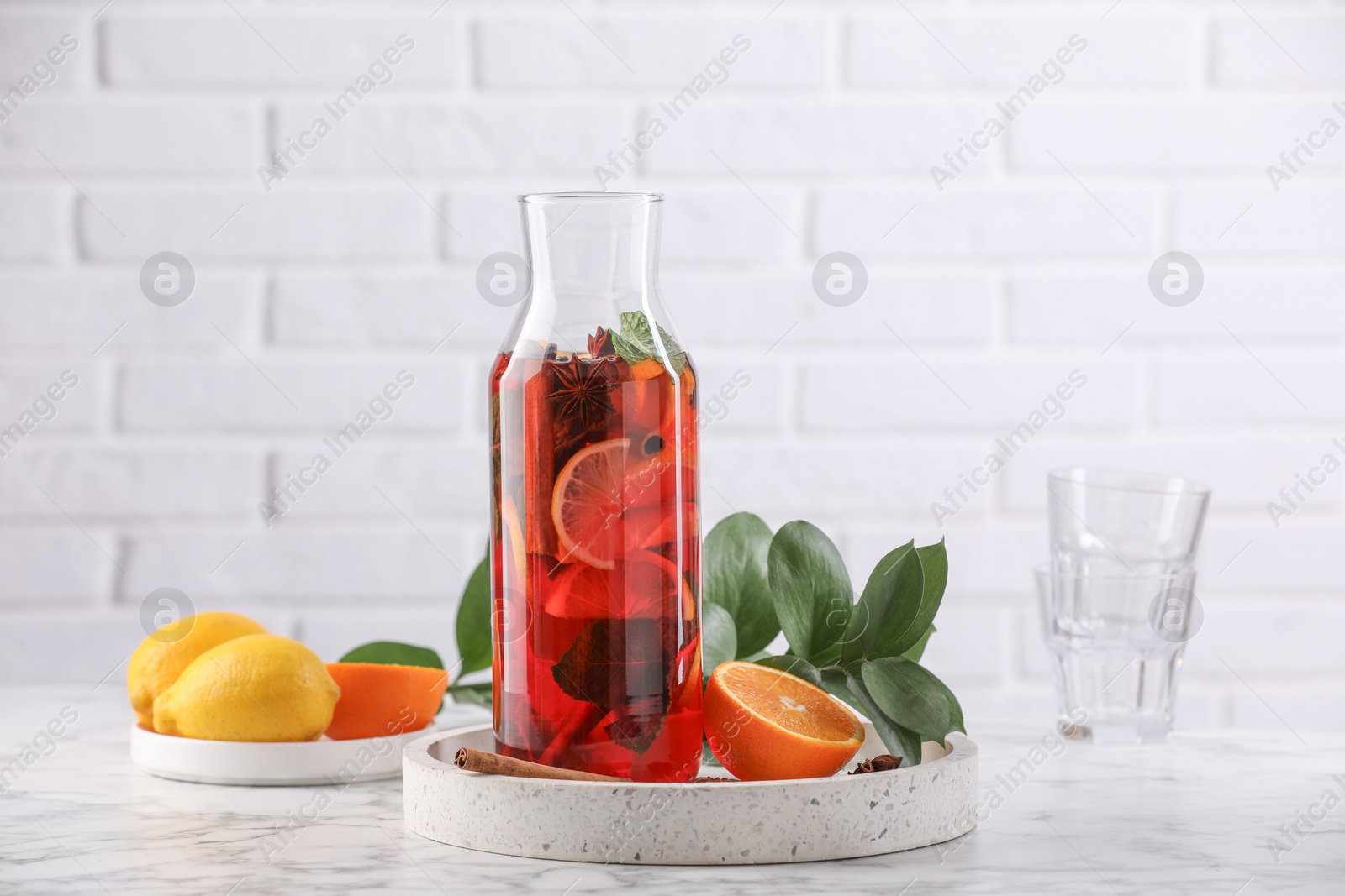 Photo of Delicious punch drink in bottle and ingredients on white marble table