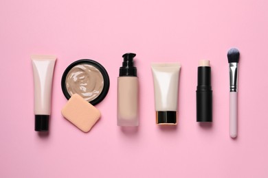 Photo of Liquid foundations and beauty accessories on pink background, flat lay