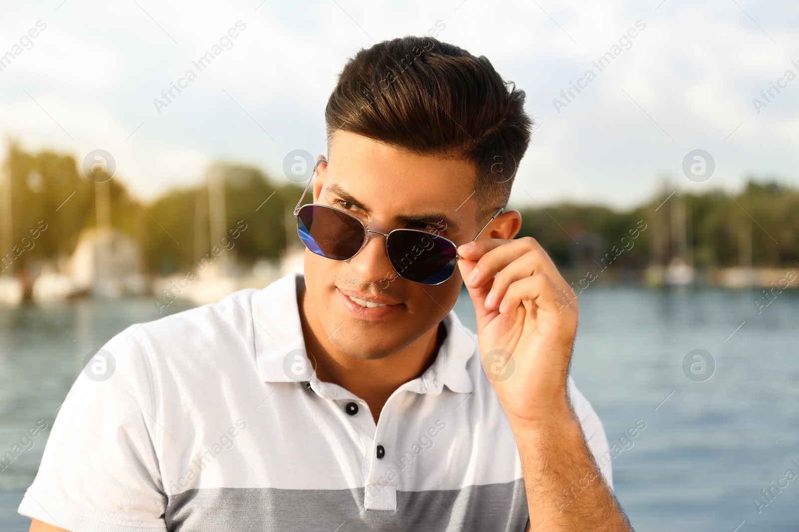 Photo of Handsome man wearing stylish sunglasses near river