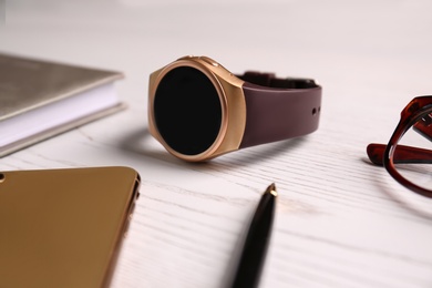 Photo of Composition with stylish smart watch on white wooden table, closeup