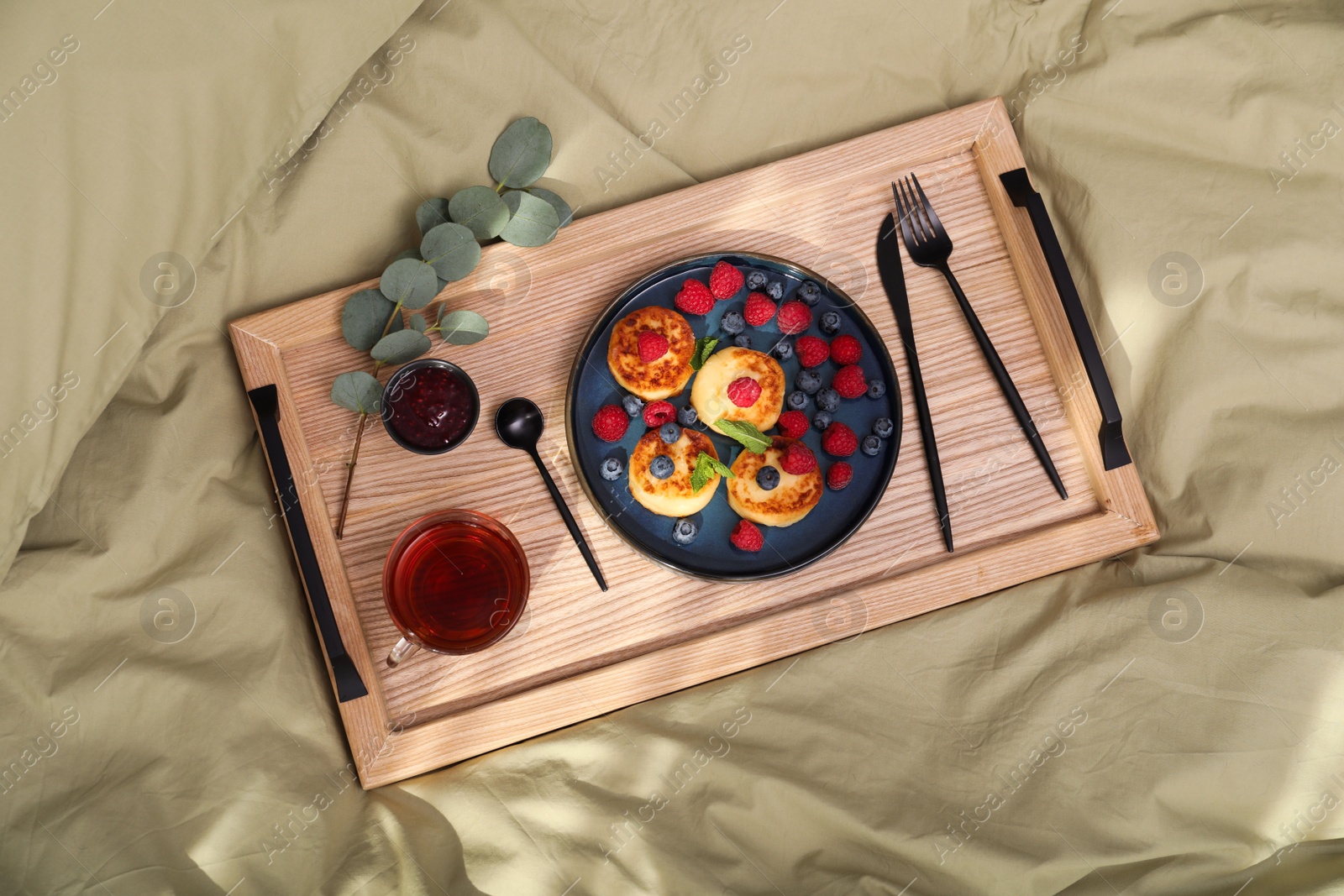 Photo of Delicious cottage cheese pancakes with fresh berries and mint served on wooden bed tray, top view