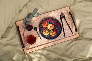 Delicious cottage cheese pancakes with fresh berries and mint served on wooden bed tray, top view