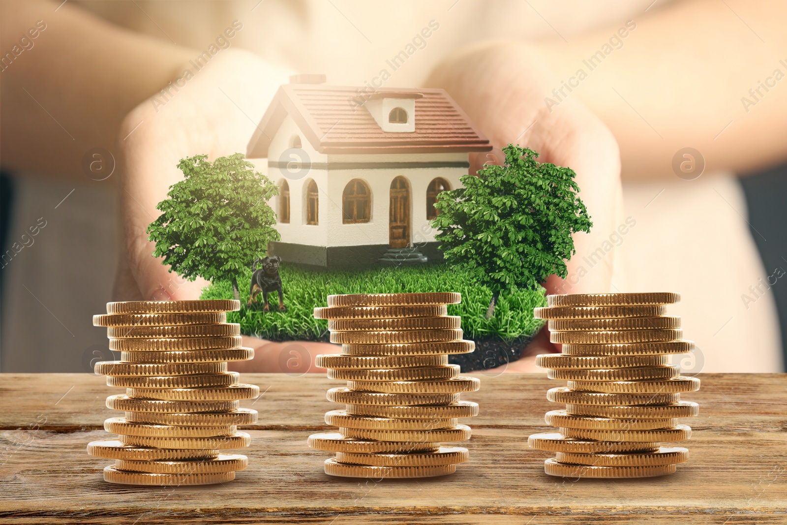 Image of Stack of coins on wooden table and woman holding house model. Real estate investing