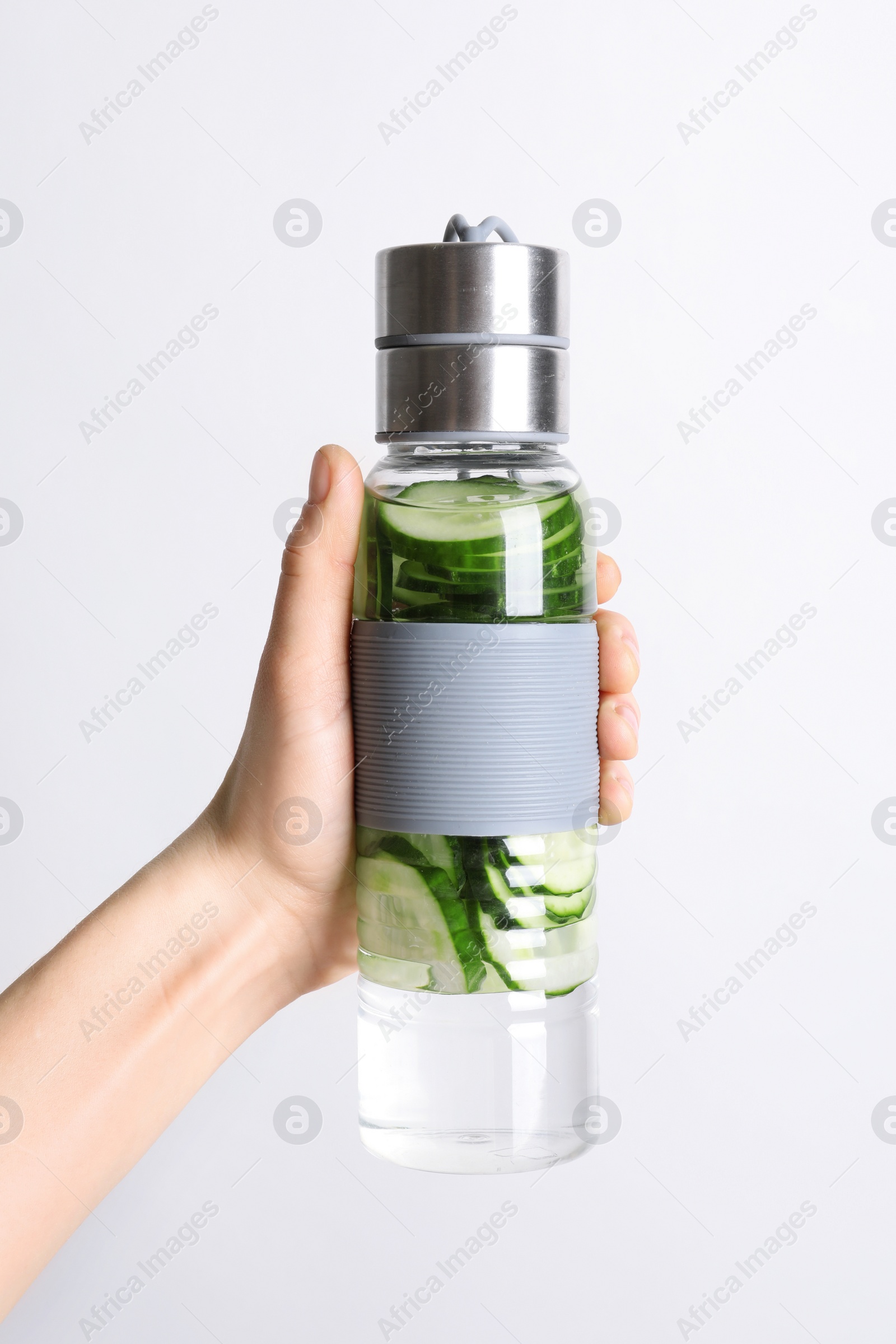 Photo of Young woman holding bottle with fresh cucumber water on white background, closeup