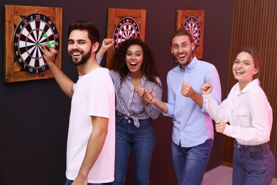 Photo of Group of friends playing darts in bar
