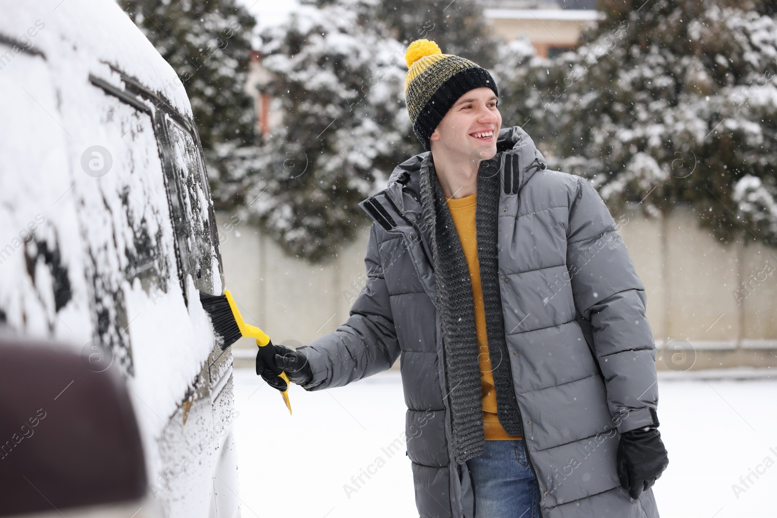 Photo of Man cleaning snow from car window outdoors