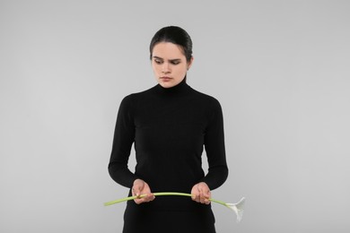 Photo of Sad woman with calla lily flower on light grey background. Funeral ceremony