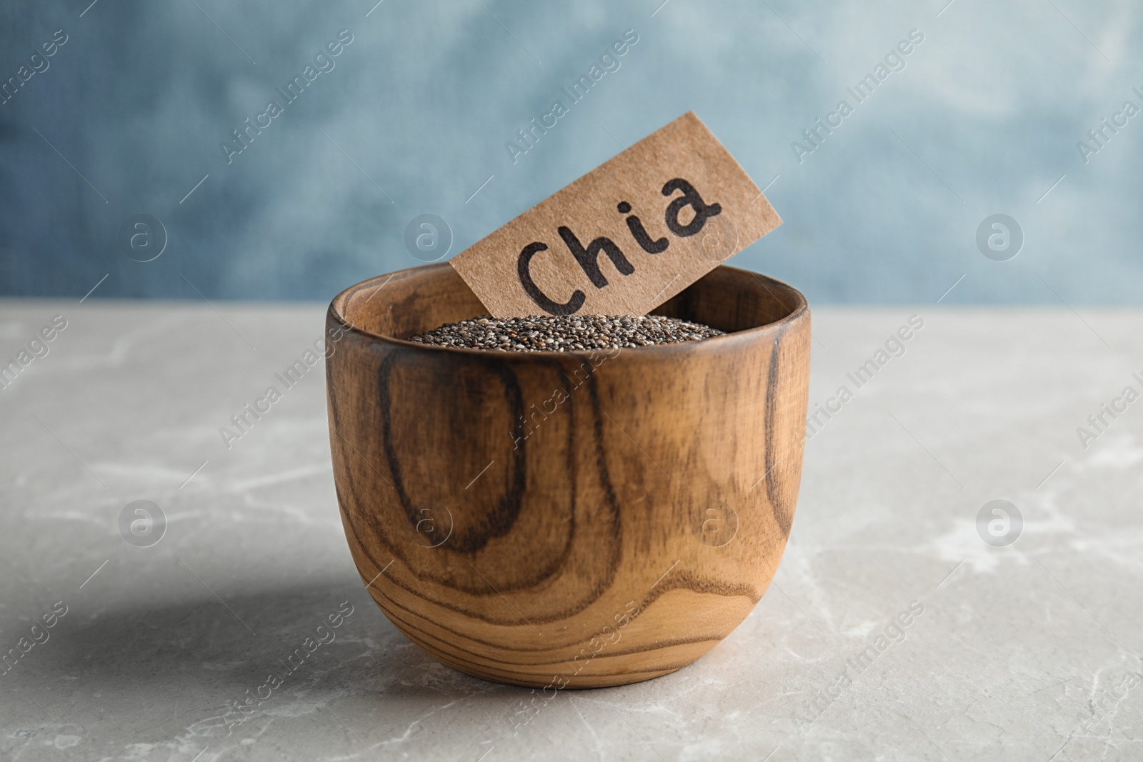 Photo of Bowl with chia seeds on table against color background