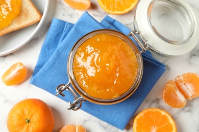 Flat lay composition with tasty tangerine jam on white marble table