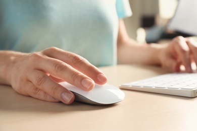 Photo of Woman using computer mouse and keyboard at table, closeup