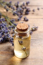 Photo of Bottle of essential oil and lavender flowers on wooden table