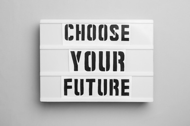 Photo of Board with words CHOOSE YOUR FUTURE on light background, top view. Career concept