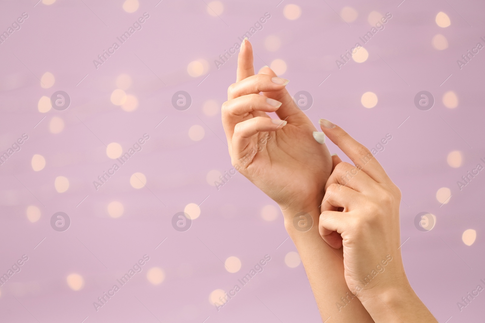 Photo of Woman applying hand cream on blurred background, closeup. Space for text