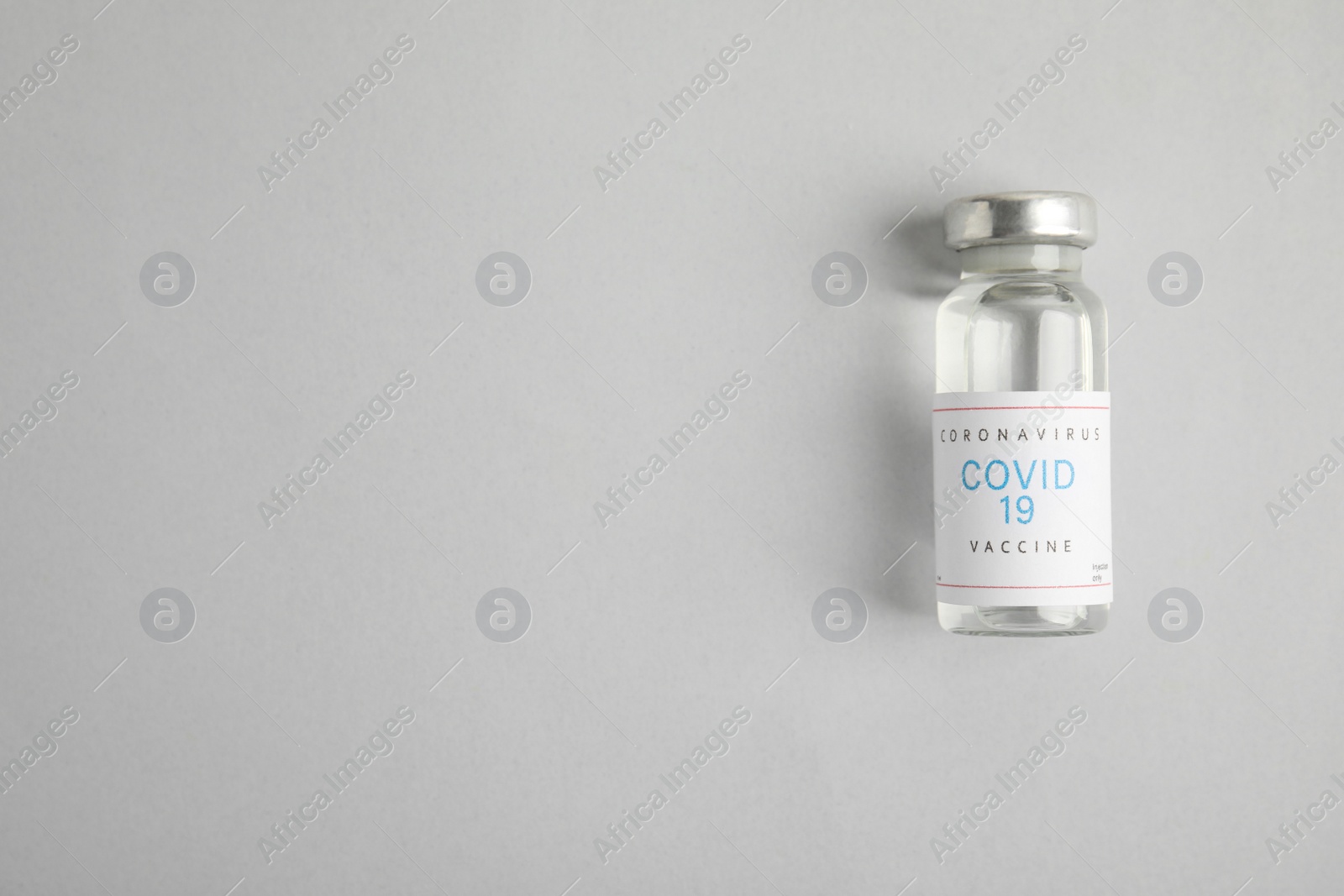 Photo of Vial with coronavirus vaccine on light background, top view. Space for text