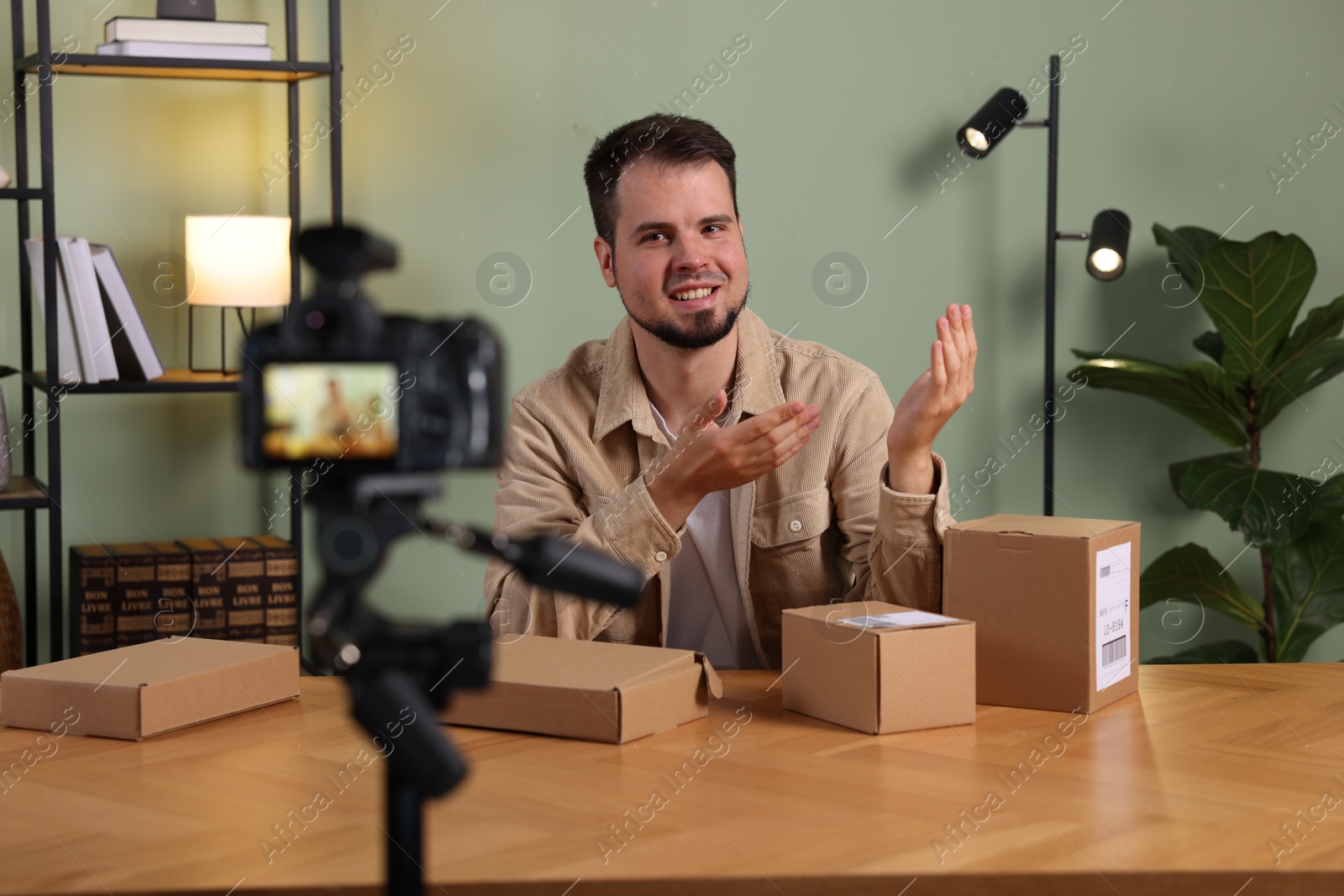 Photo of Smiling blogger with many parcels recording video at home