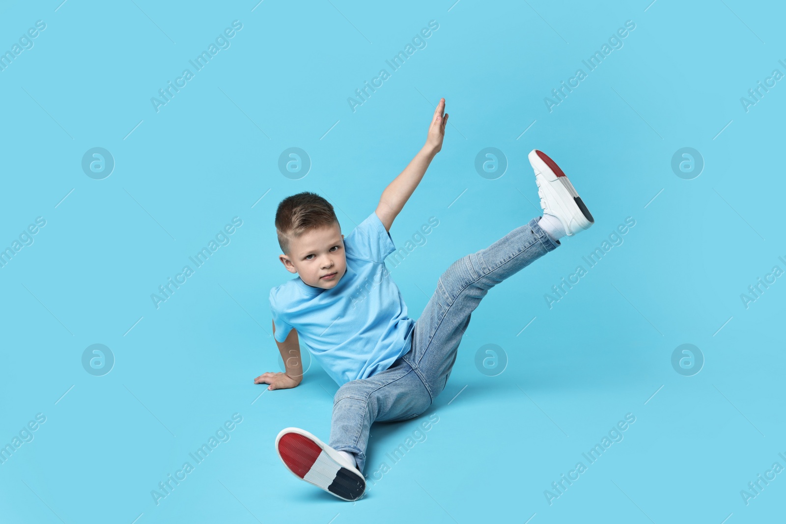 Photo of Happy little boy dancing on light blue background