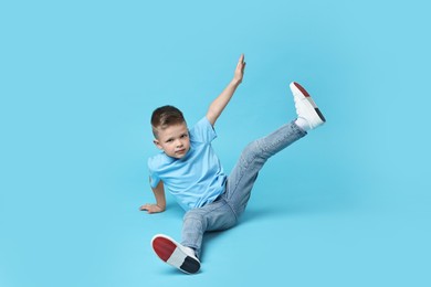 Photo of Happy little boy dancing on light blue background