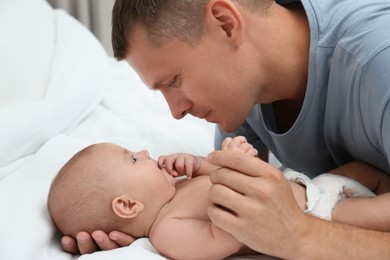 Photo of Father with his cute baby on bed
