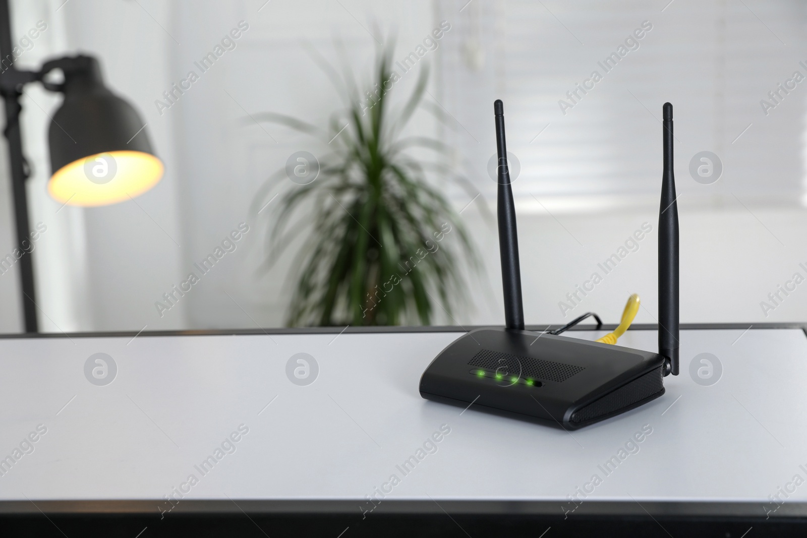 Photo of Modern Wi-Fi router on table indoors. Space for text