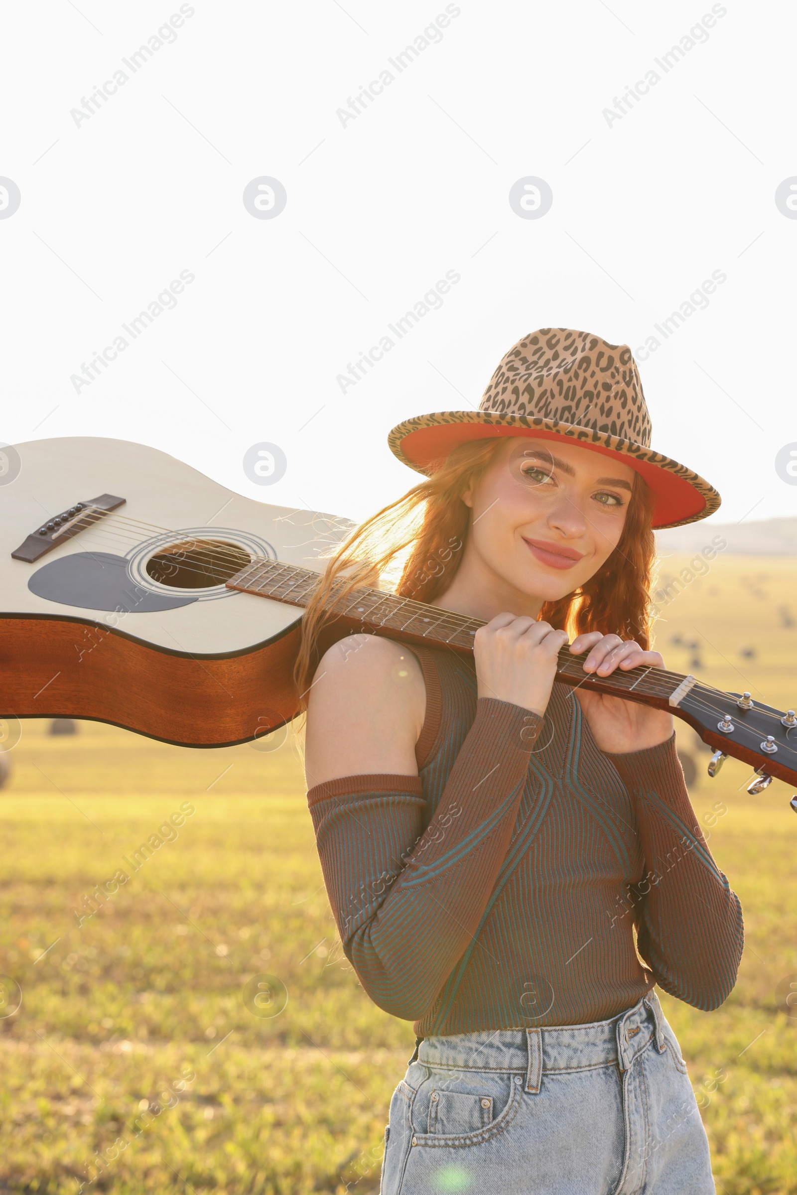 Photo of Beautiful happy hippie woman with guitar in field